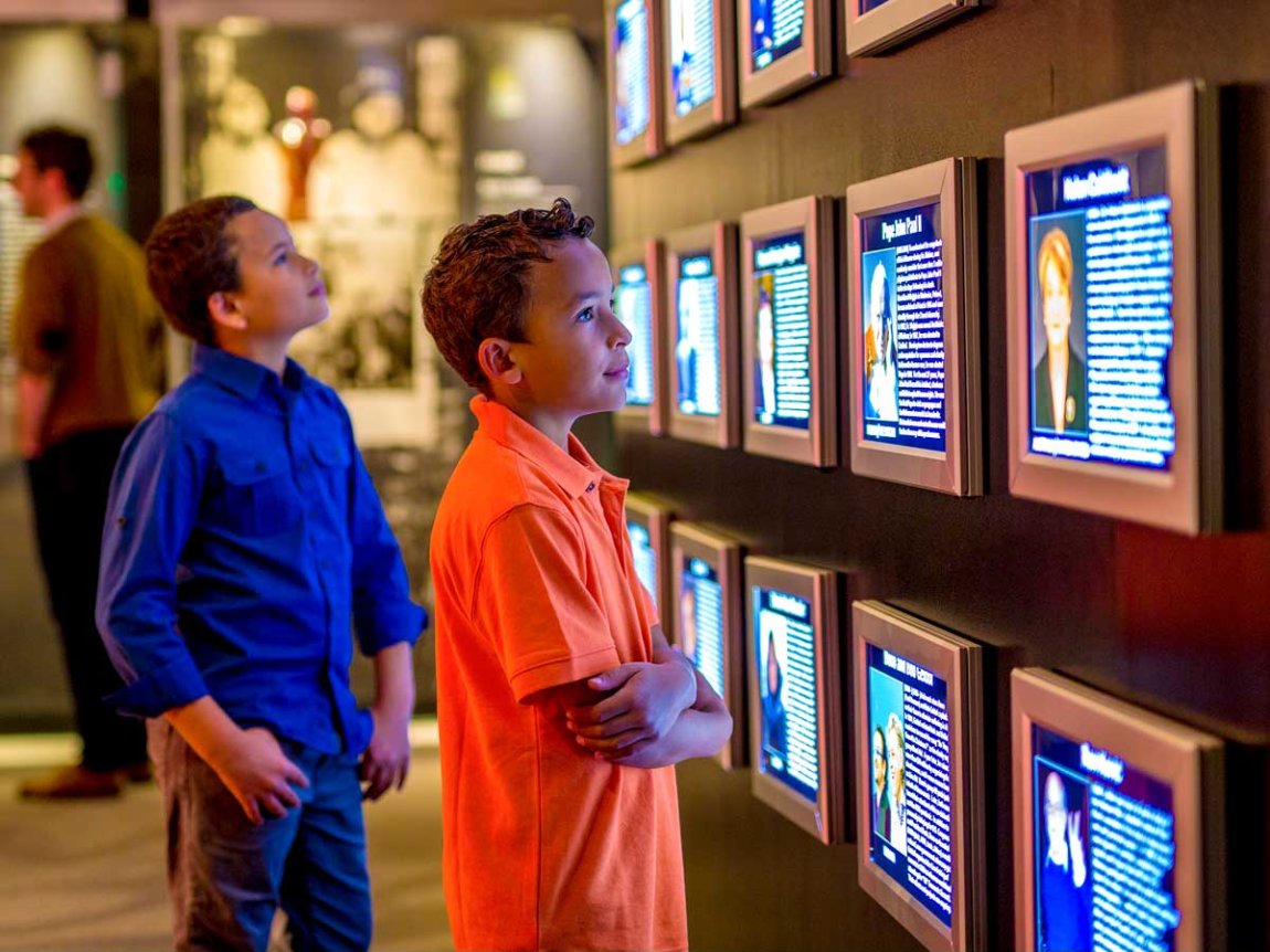 museum visitors gaze at an array of screens in an exhibit
