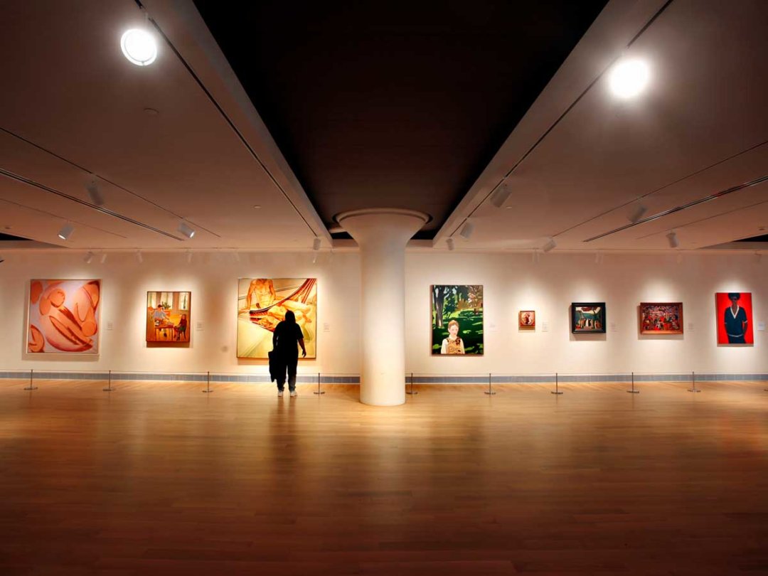 visitors examine art on the walls in a large open gallery