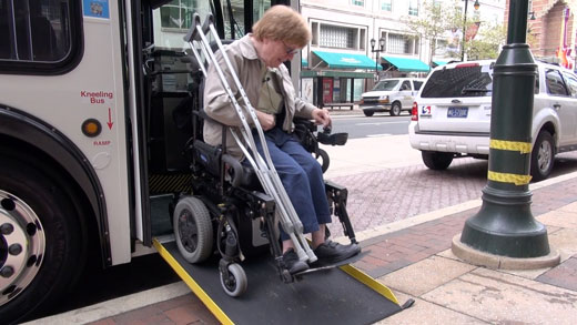 a passenger in a wheelchair exits a bus by ramp